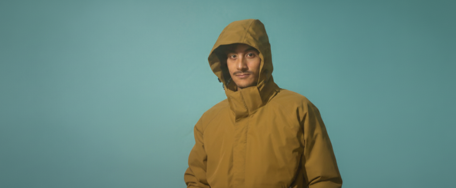 Hood up on the Dainik daily jacket, storm collar fastened to the chin